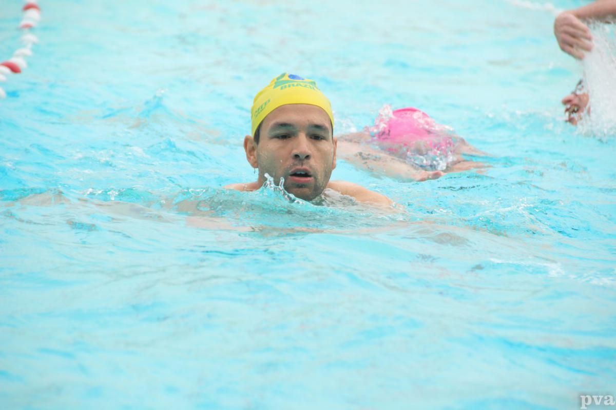 Triathlon Eibergen. Een man met een gele badmuts zwemt in een zwembad.