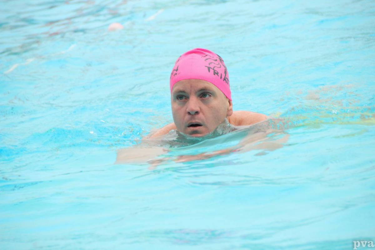 Triathlon Eibergen. Een man met een roze badmuts zwemt in een zwembad.