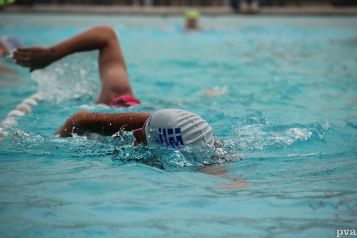 Triathlon Eibergen. Iemand zwemt in een zwembad en draagt ​​een badmuts.
