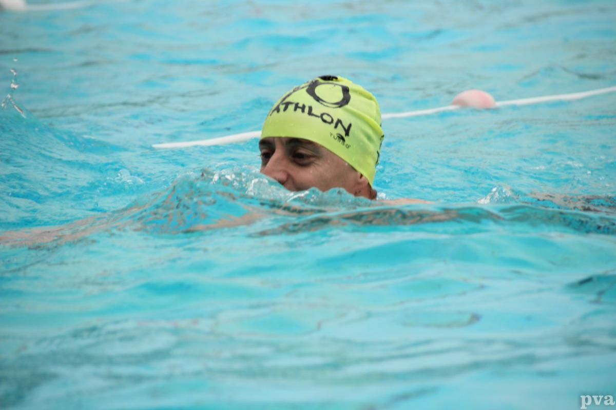 Triathlon Eibergen. Een persoon met een gele badmuts zwemt in een zwembad.