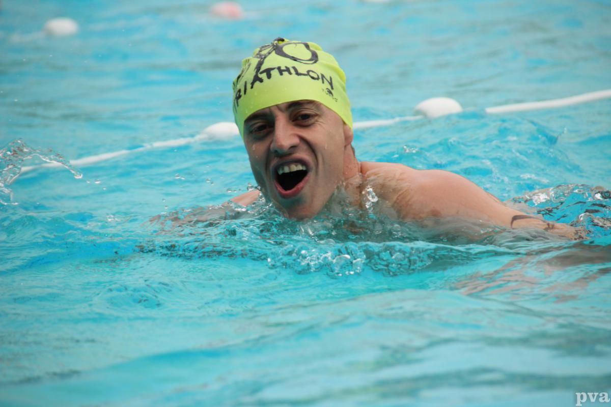 Triathlon Eibergen. Een man met een gele badmuts zwemt in een zwembad.