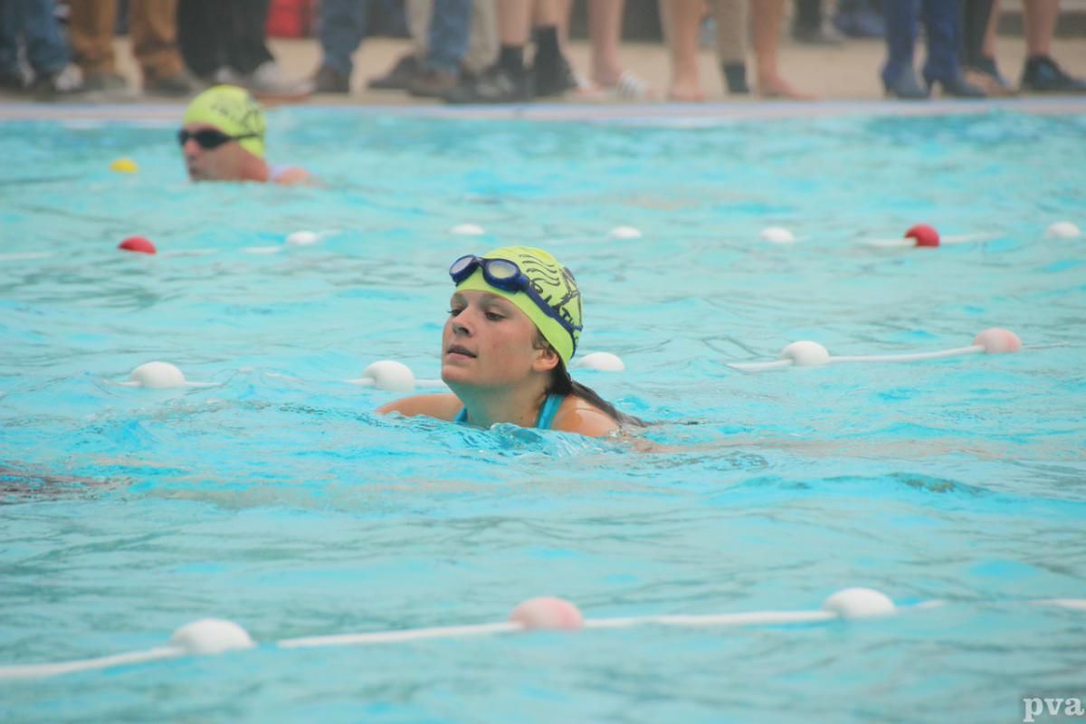 Triathlon Eibergen. Een vrouw zwemt in een zwembad met een gele badmuts en een zwembril.
