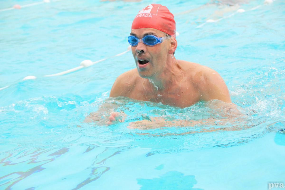 Triathlon Eibergen. Een man zwemt in een zwembad met een rode hoed en een duikbril.