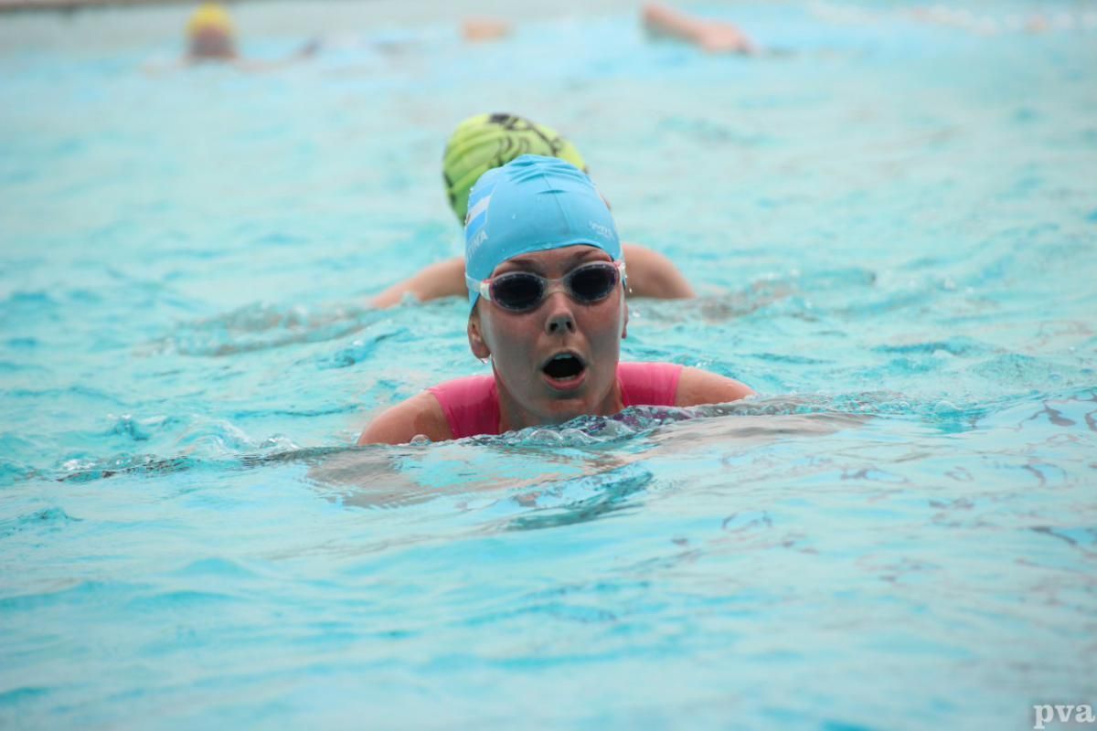 Triathlon Eibergen. Een vrouw zwemt in een zwembad met een verbaasde blik op haar gezicht.