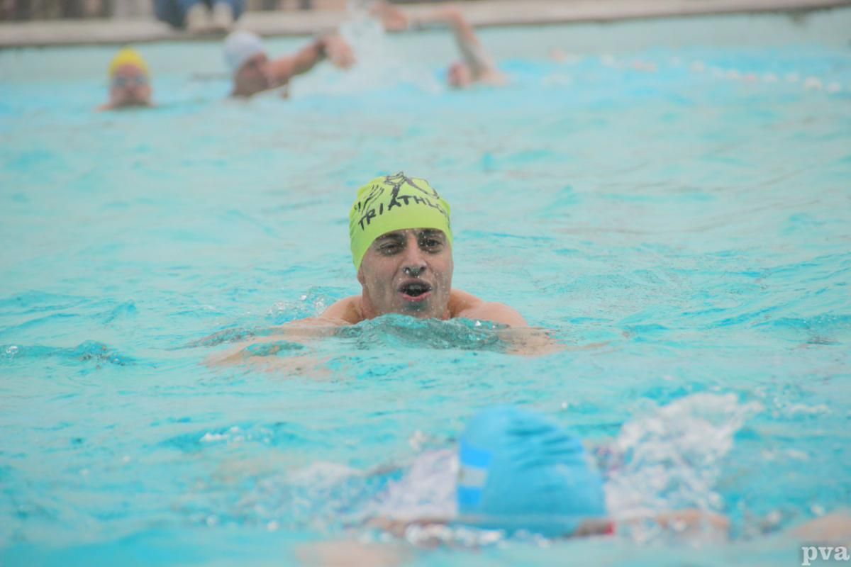 Triathlon Eibergen. Een man met een gele badmuts zwemt in een zwembad.
