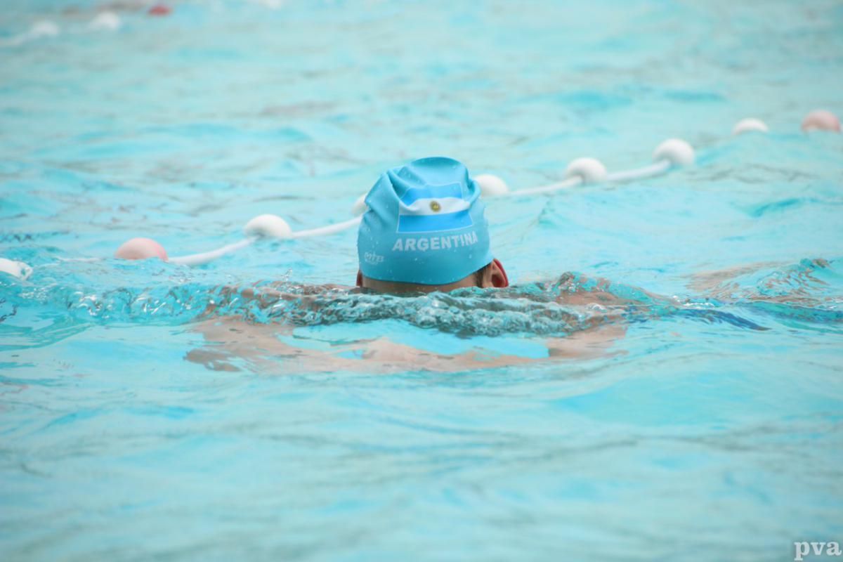 Triathlon Eibergen. Een persoon met een blauwe badmuts zwemt in een zwembad.
