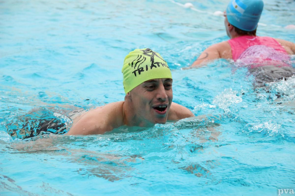 Triathlon Eibergen. Een man met een gele badmuts zwemt in een zwembad.
