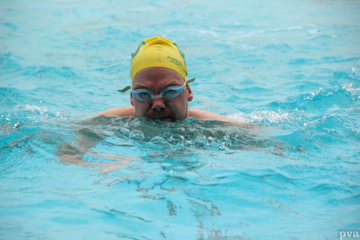 Triathlon Eibergen. Een man zwemt in een zwembad met een gele badmuts en een duikbril.