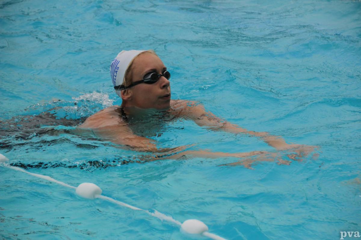 Triathlon Eibergen. Iemand zwemt in een zwembad met een badmuts en een zwembril op.