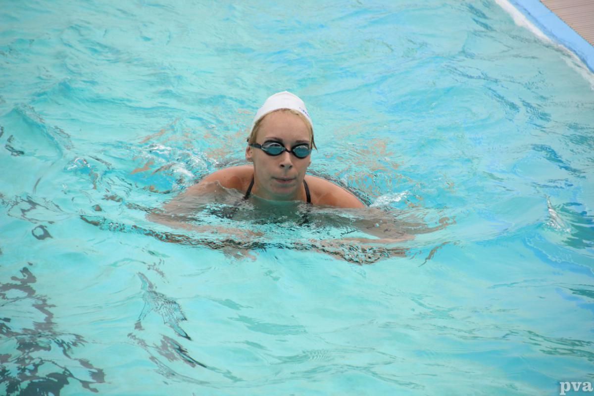 Triathlon Eibergen. Een vrouw zwemt in een zwembad met een badmuts en een zwembril op.