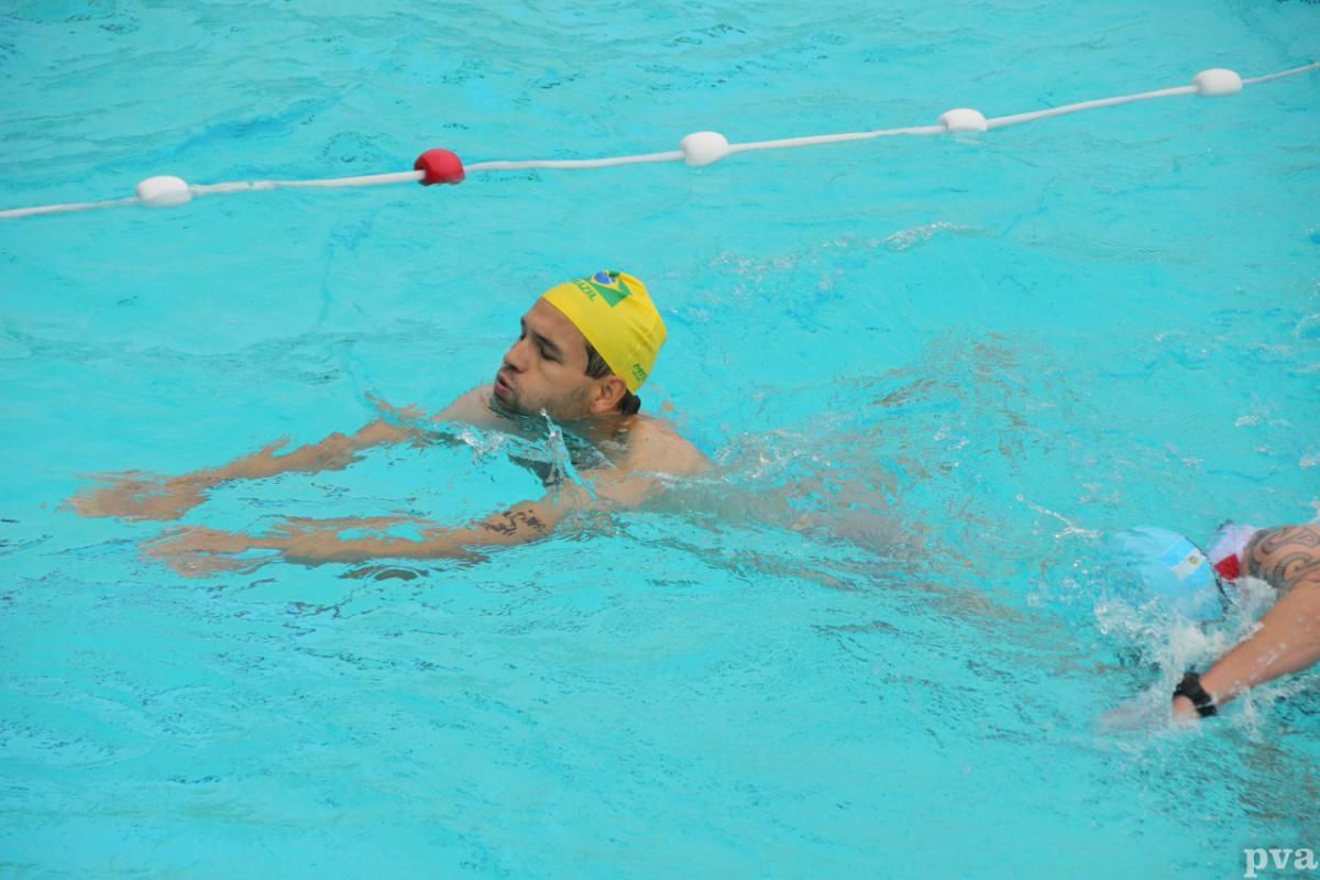 Triathlon Eibergen. Een man met een gele badmuts zwemt in een zwembad.