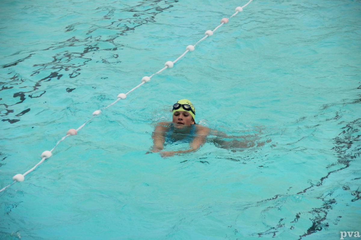Triathlon Eibergen. Iemand zwemt in een zwembad met een gele badmuts en een duikbril op.