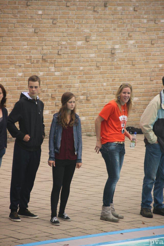 Triathlon Eibergen. Een groep mensen staat voor een bakstenen muur.