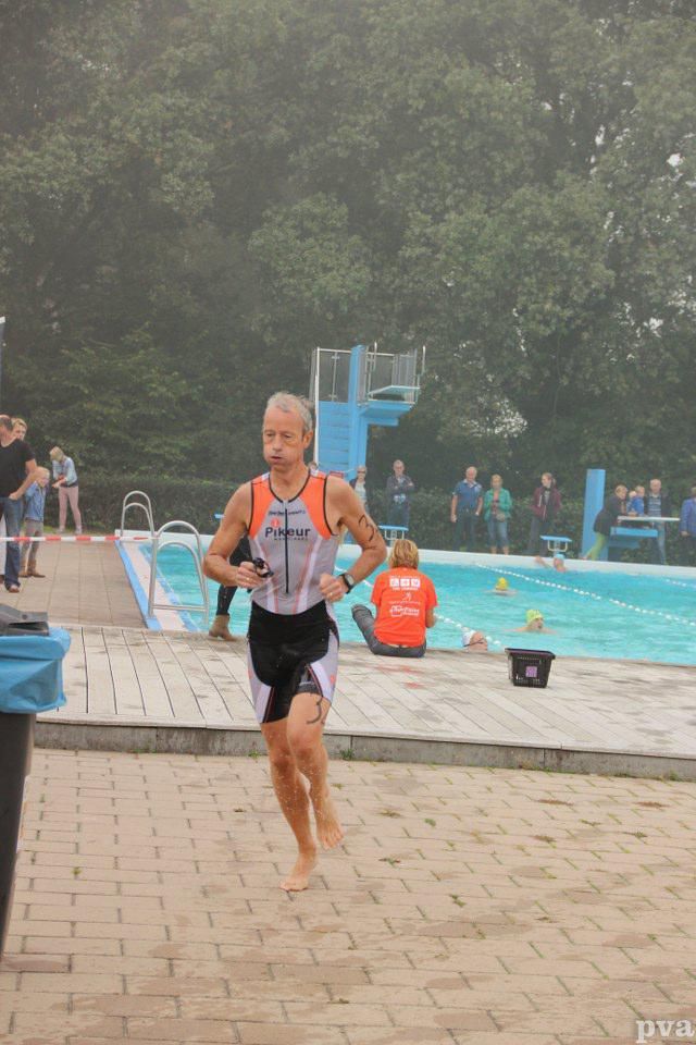 Triathlon Eibergen. Een man rent voor een zwembad.