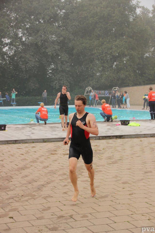 Triathlon Eibergen. Een man in een wetsuit rent voor een zwembad