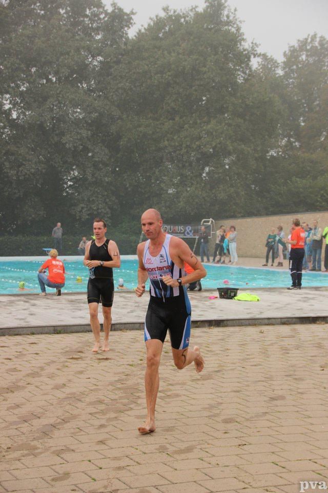 Triathlon Eibergen. Een man rent voor een zwembad.