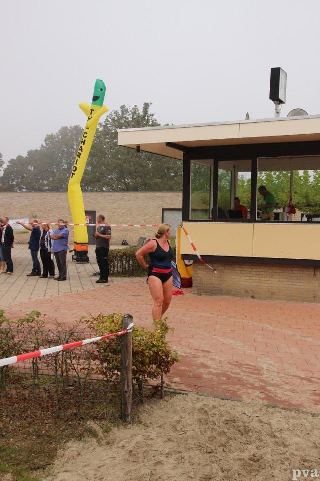 Triathlon Eibergen. Een vrouw in een badpak staat voor een gebouw