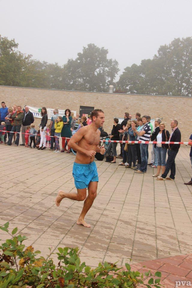 Triathlon Eibergen. Een man zonder shirt in een blauwe korte broek rent voor een menigte mensen uit.