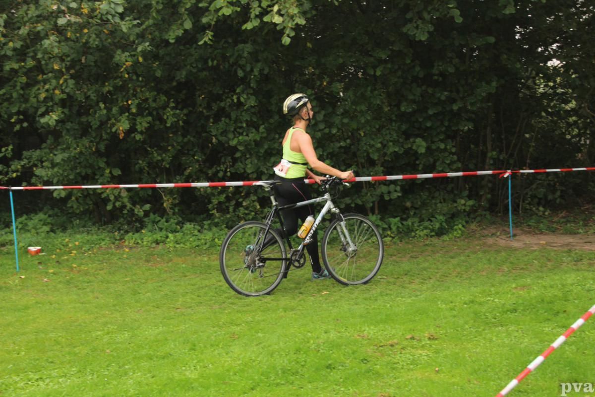 Triathlon Eibergen. Een vrouw fietst op een grasveld.