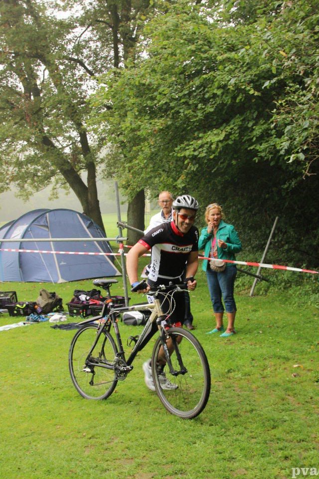 Triathlon Eibergen. Een man fietst op een grasveld.