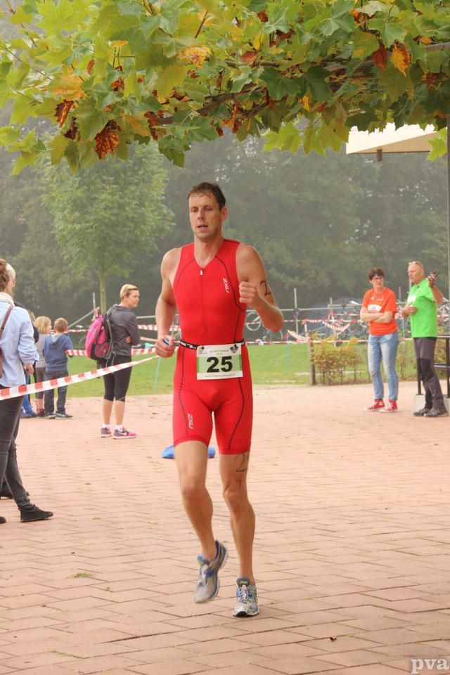 Triathlon Eibergen. Een man in een rood pak rent met het nummer 25 op zijn middel.