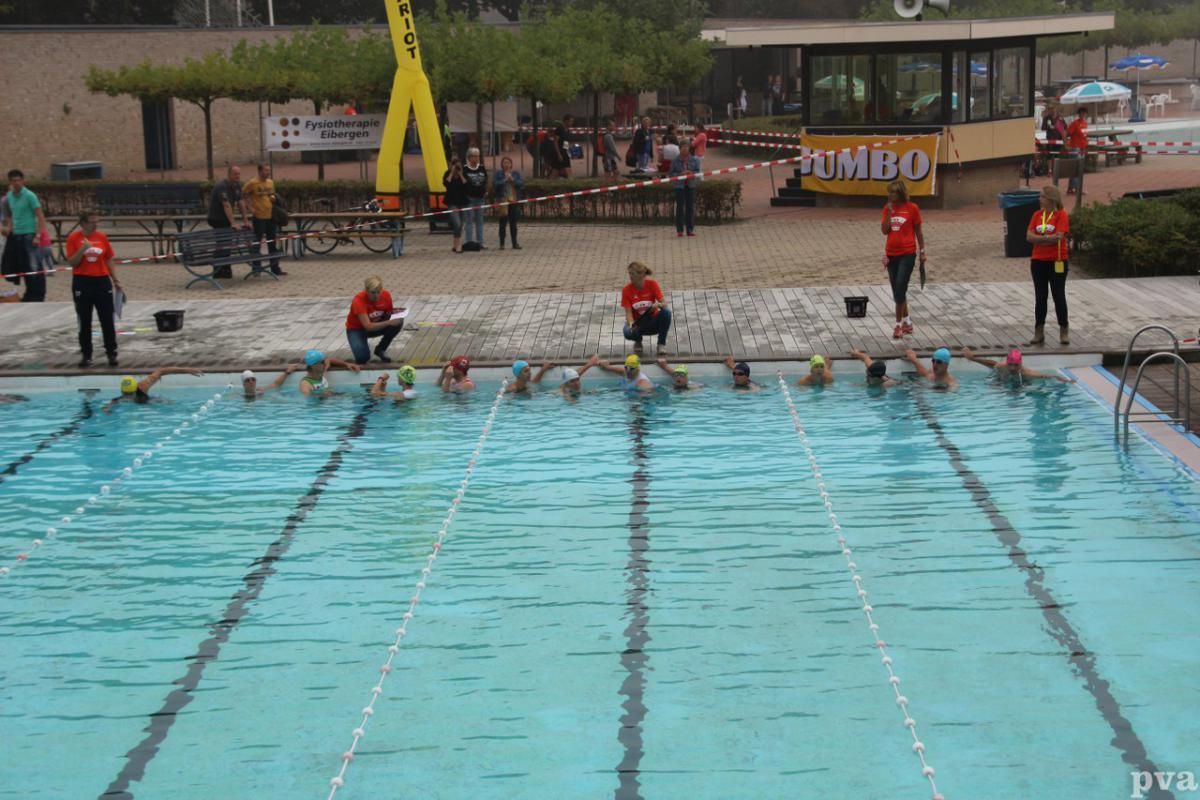 Triathlon Eibergen. Een groep mensen zit op de rand van een zwembad.
