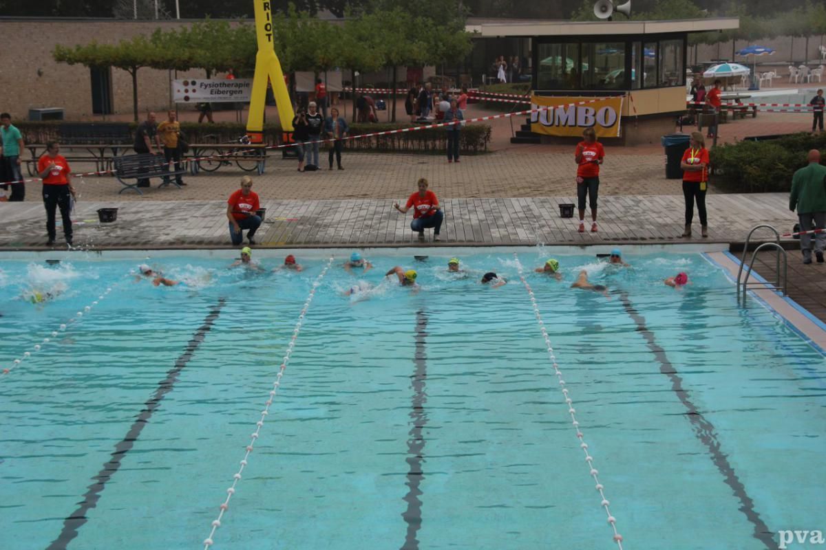 Triathlon Eibergen. Een groep mensen zwemt in een zwembad met op de achtergrond een bord met de tekst malibu