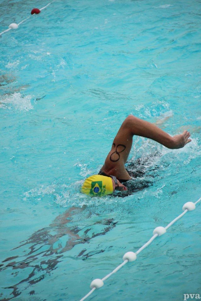 Triathlon Eibergen. Iemand zwemt in een zwembad met een gele badmuts op.