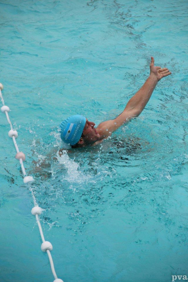 Triathlon Eibergen. Een man zwemt in een zwembad met zijn arm uitgestrekt.
