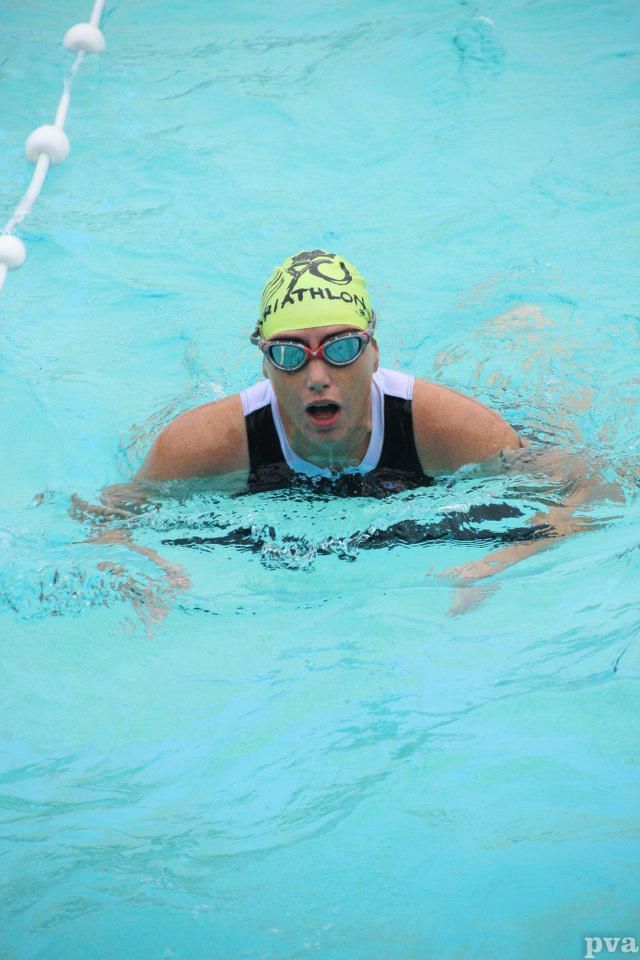 Triathlon Eibergen. Een vrouw zwemt in een zwembad met een badmuts en een zwembril op.