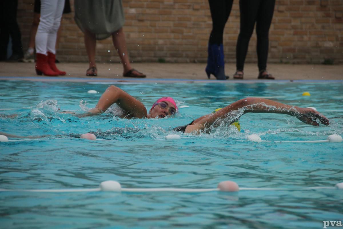 Triathlon Eibergen. Een vrouw zwemt in een zwembad terwijl mensen toekijken.