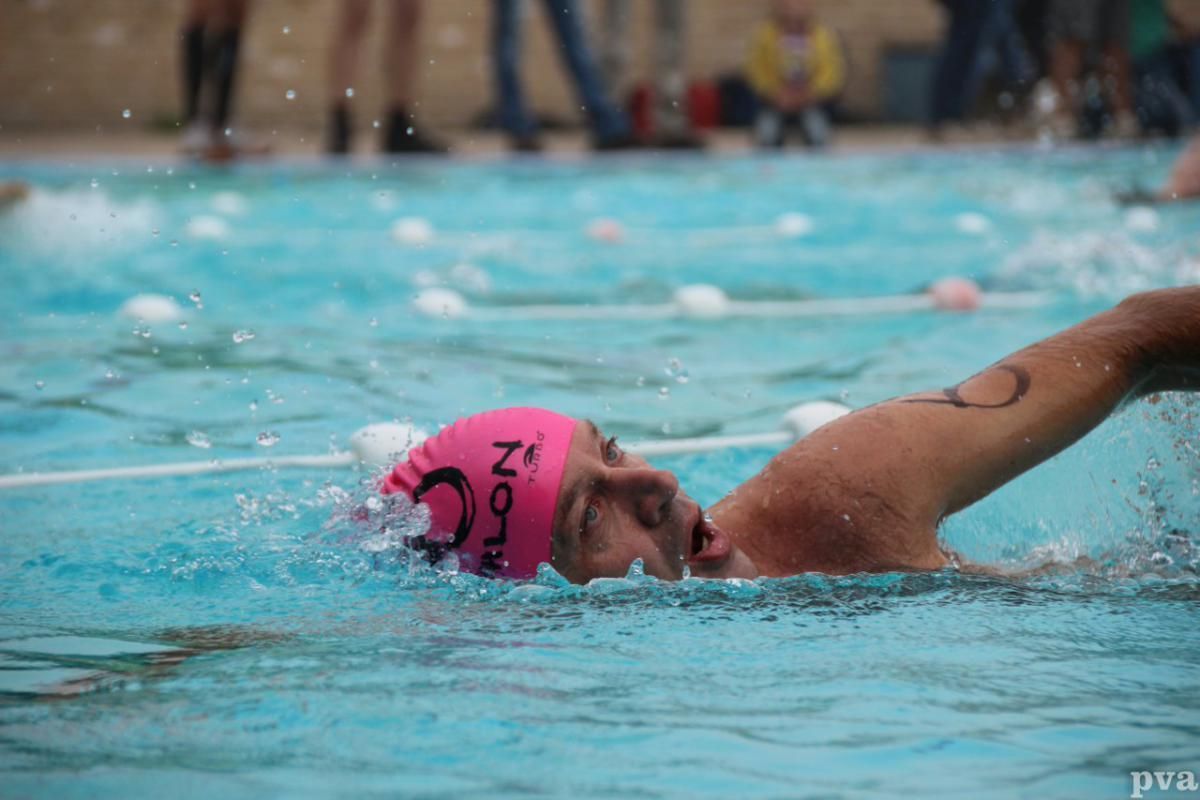 Triathlon Eibergen. Een man met een roze badmuts zwemt in een zwembad.