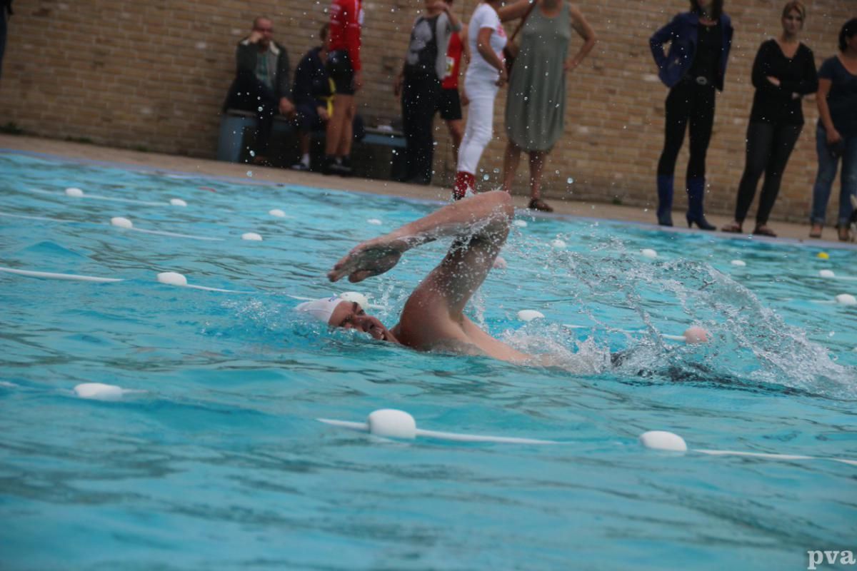 Triathlon Eibergen. Een man zwemt in een zwembad terwijl mensen toekijken.