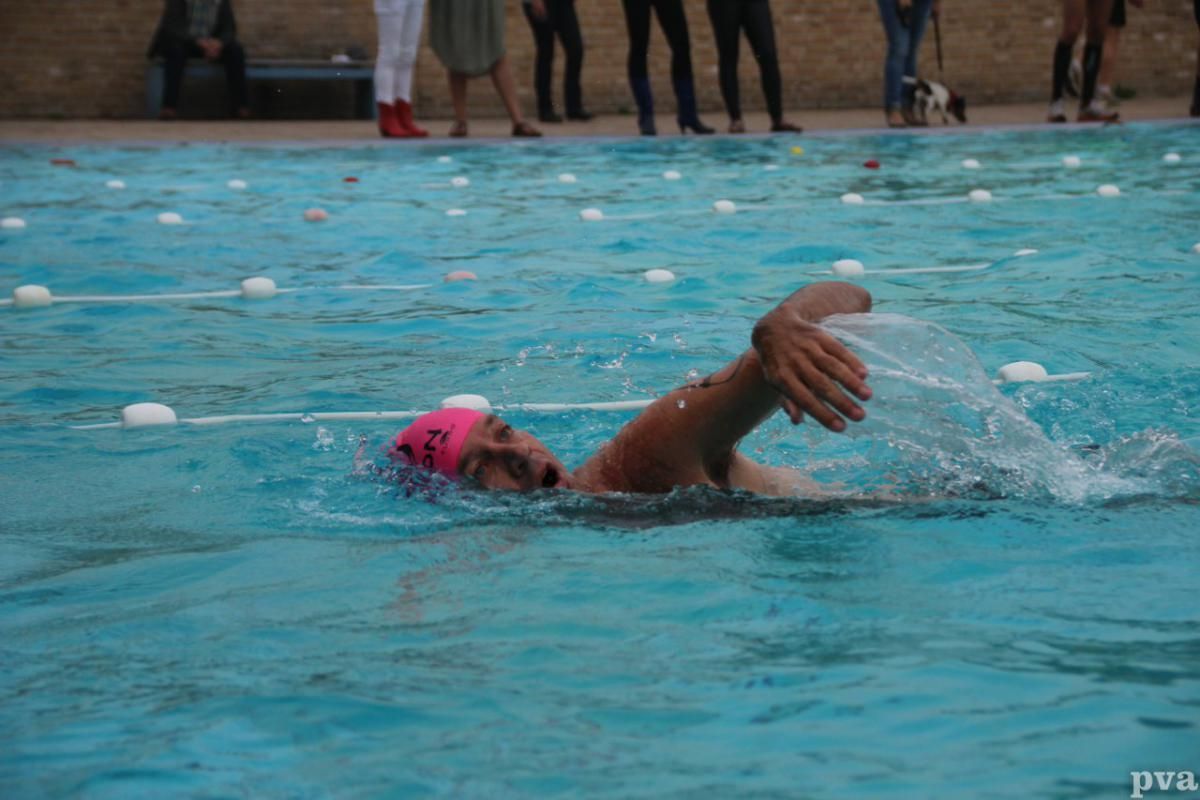 Triathlon Eibergen. Iemand zwemt in een zwembad met een roze hoed op.