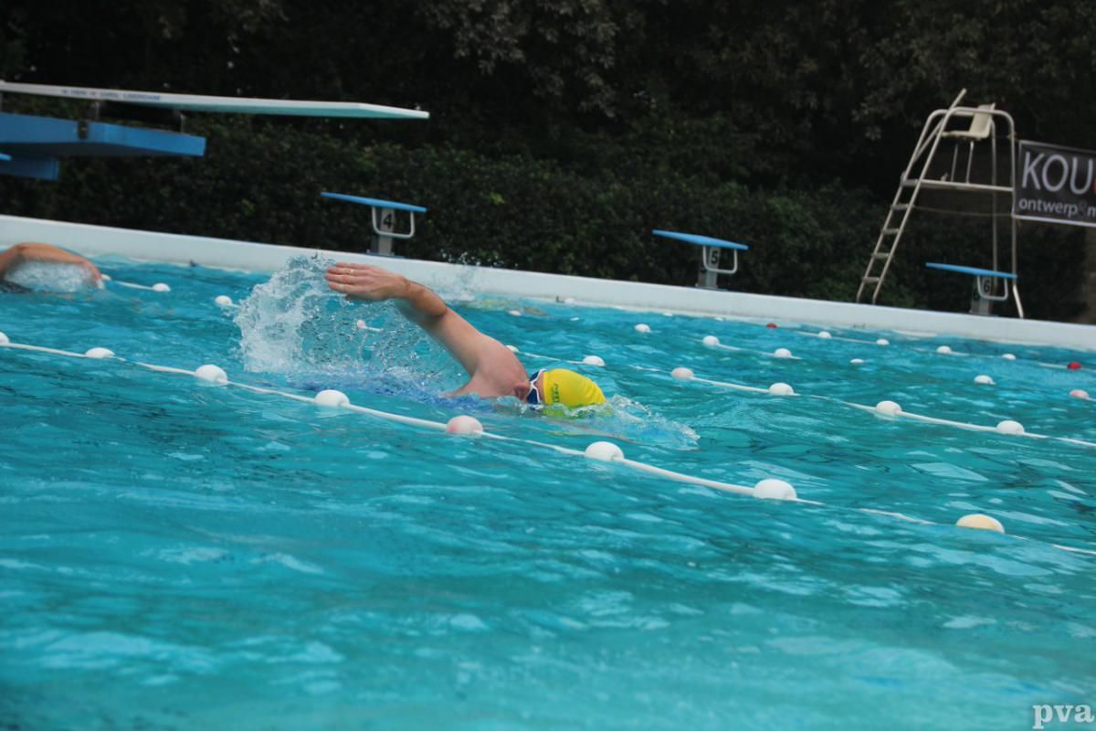 Triathlon Eibergen. Een man zwemt in een zwembad met een bord waarop staat kou