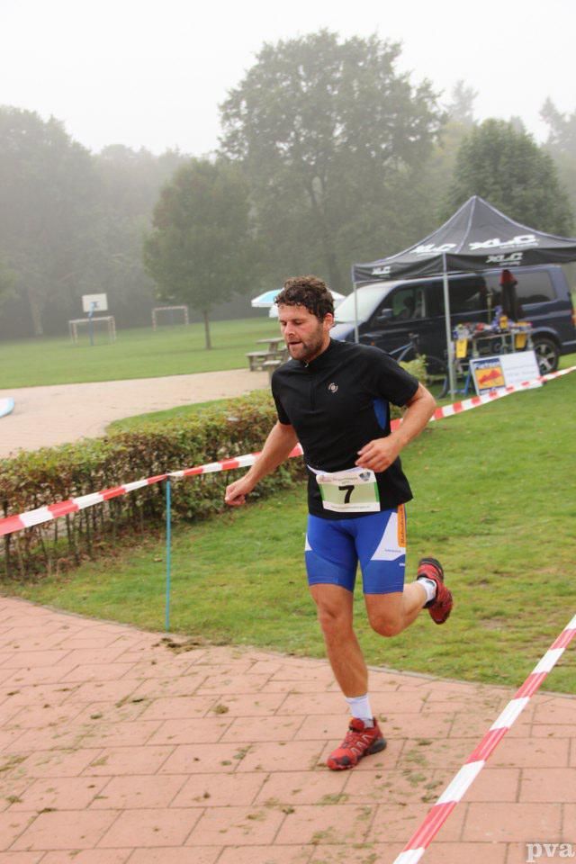 Triathlon Eibergen. Een man rent mee aan een race met een nummer 7 om zijn middel.