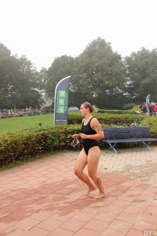 Triathlon Eibergen. Een vrouw in een zwart badpak rent op een stoep van bakstenen.
