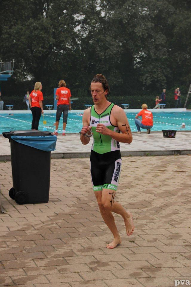 Triathlon Eibergen. Een man rent voor een zwembad.