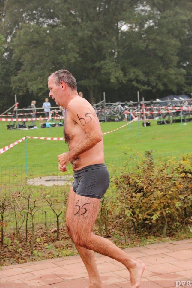 Triathlon Eibergen. Een man zonder shirt in zwembroek rent door een park.