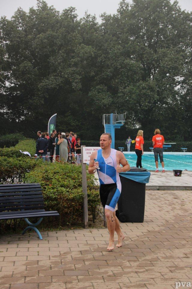 Triathlon Eibergen. Een man rent voor een zwembad.