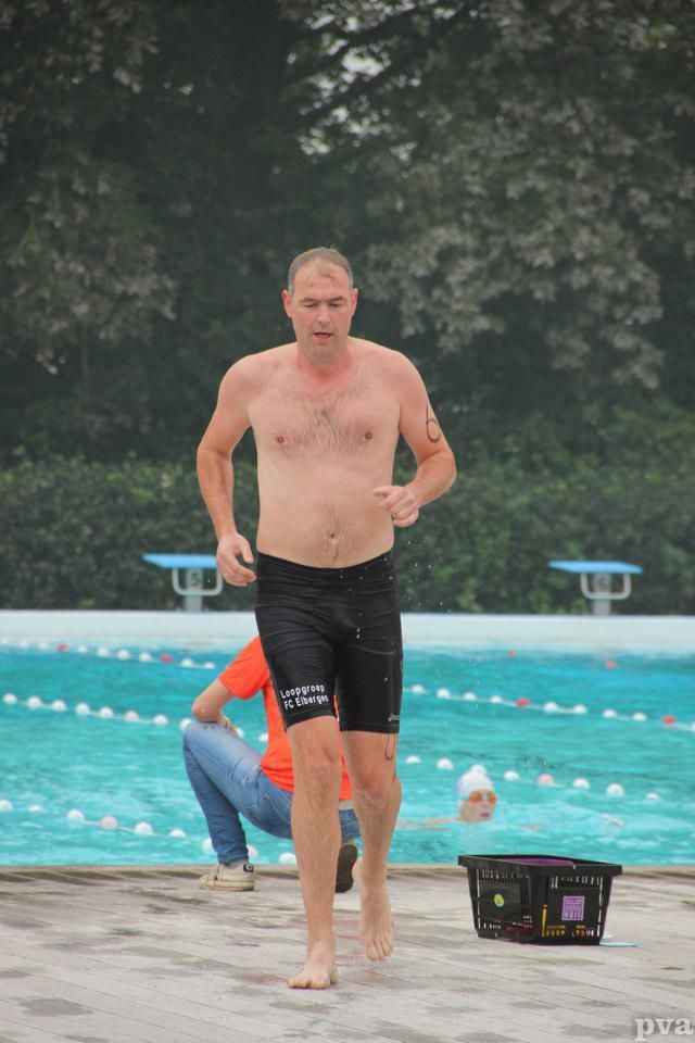 Triathlon Eibergen. Een man zonder shirt rent voor een zwembad.