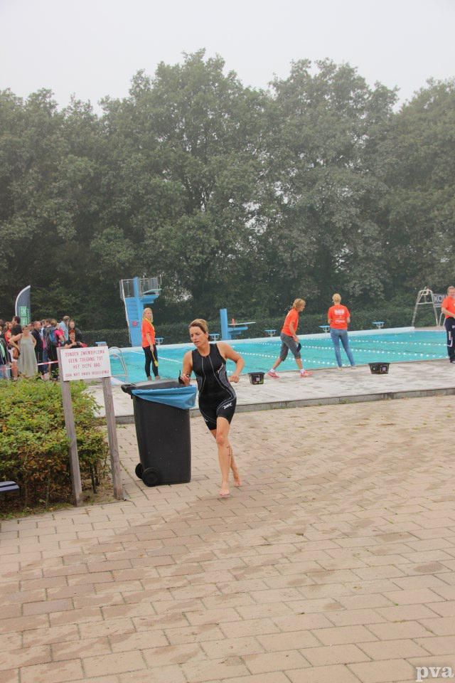 Triathlon Eibergen. Een vrouw rent voor een zwembad.