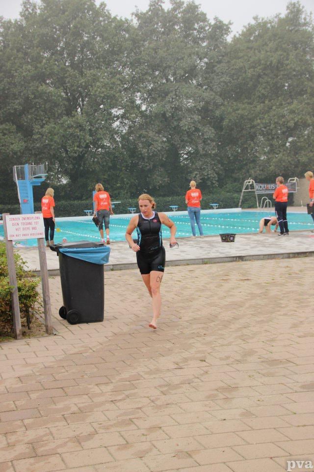 Triathlon Eibergen. Een vrouw rent voor een zwembad.