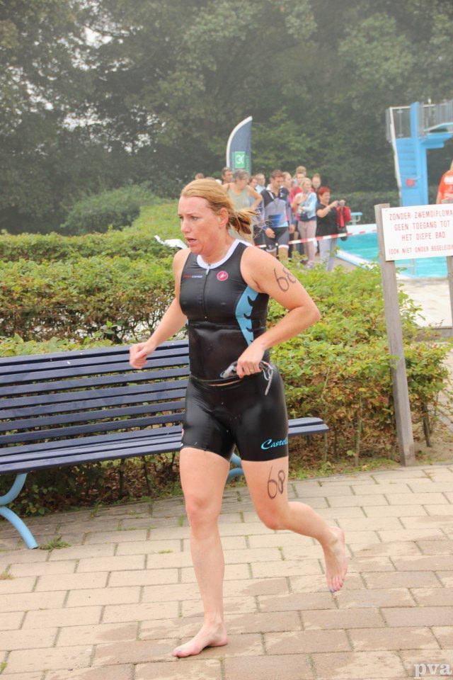 Een vrouw in een wetsuit rent voor een zwembad.