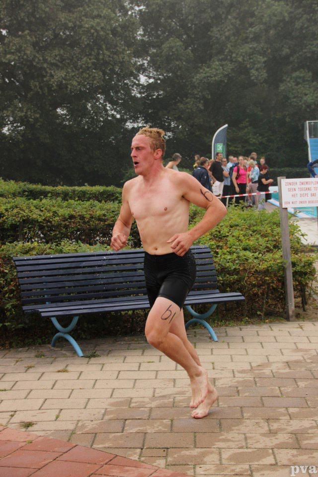 Een man zonder shirt rent voor een blauwe bank.