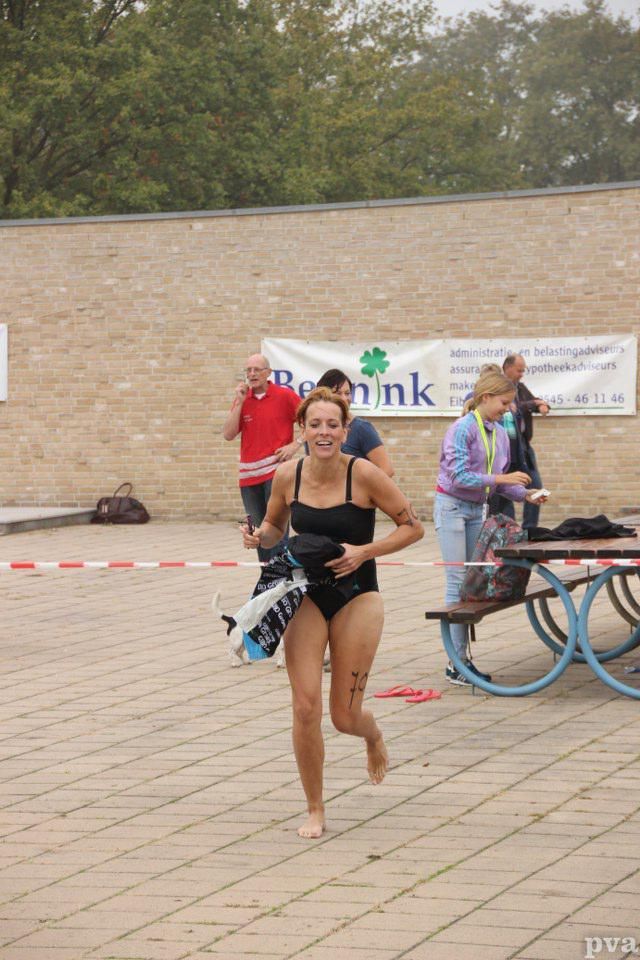 Een vrouw in een zwart badpak rent in een park.