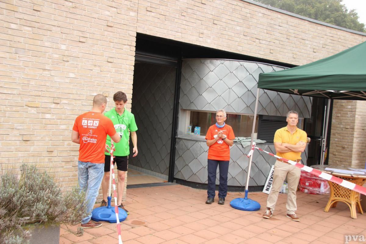 Een groep mensen die voor een gebouw met een groene tent staat