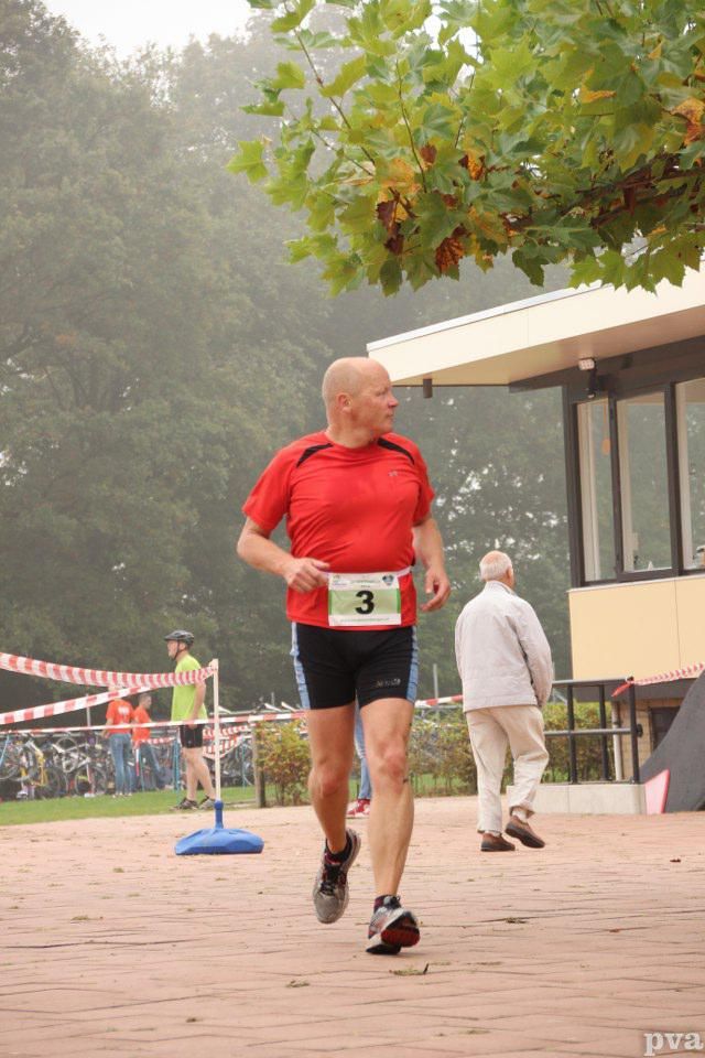 Een man in een rood shirt en een zwarte korte broek rent met het nummer 3 op zijn riem.