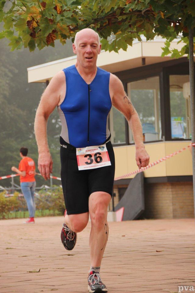 Een man in een blauw tanktopje en zwarte shorts heeft het nummer 36 op zijn tailleband