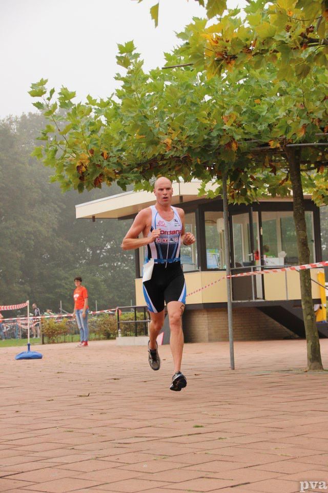 Een man rent op een stenen weg met bomen op de achtergrond
